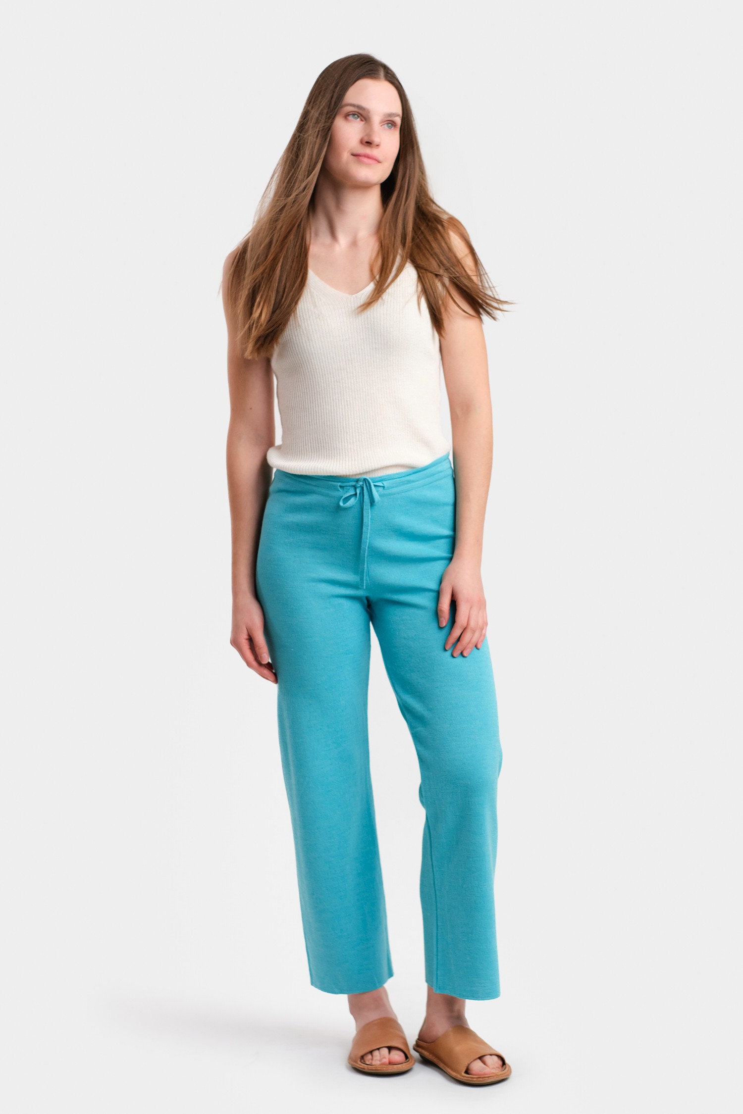 Turquoise coloured pants made from alpaca wool against a green backdrop in a studio